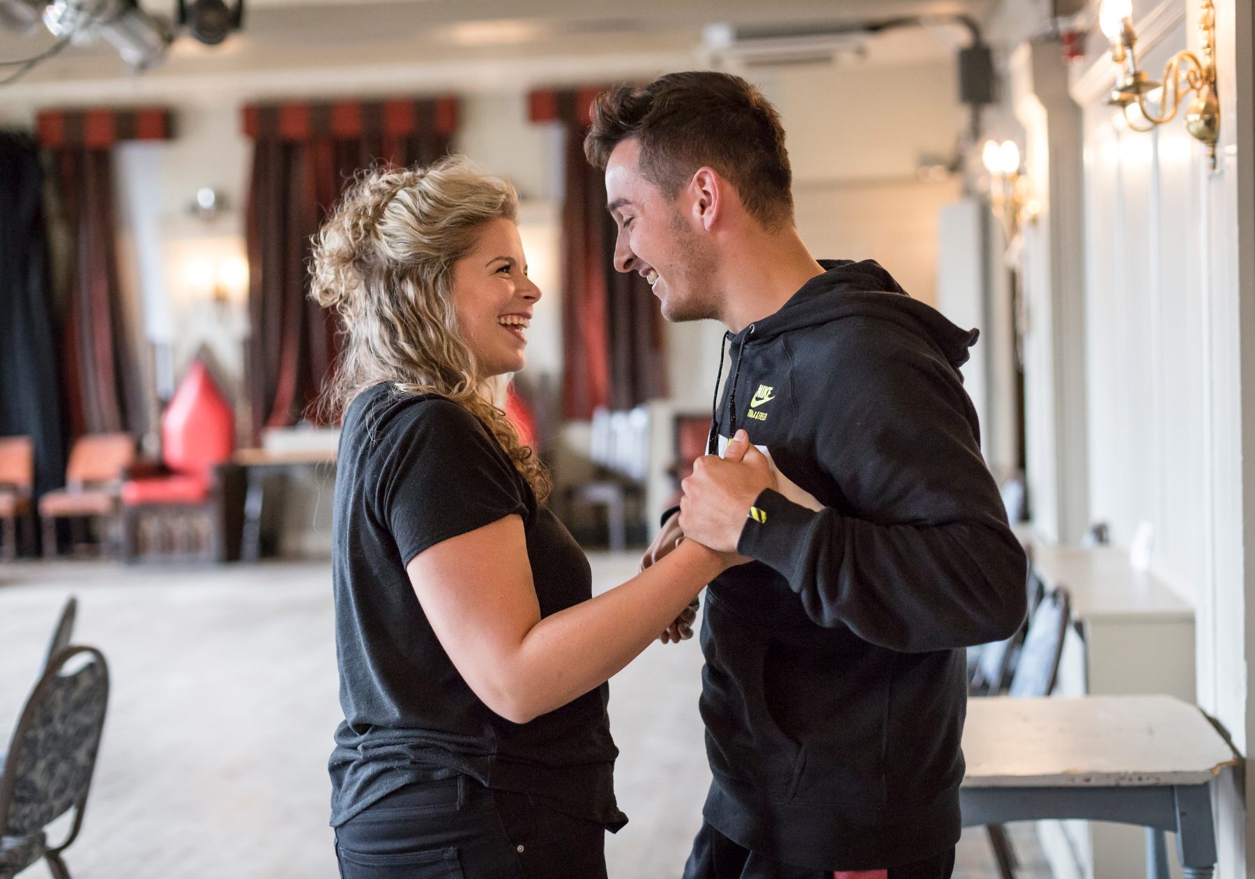Two actors holding hands and laughing in the studio
