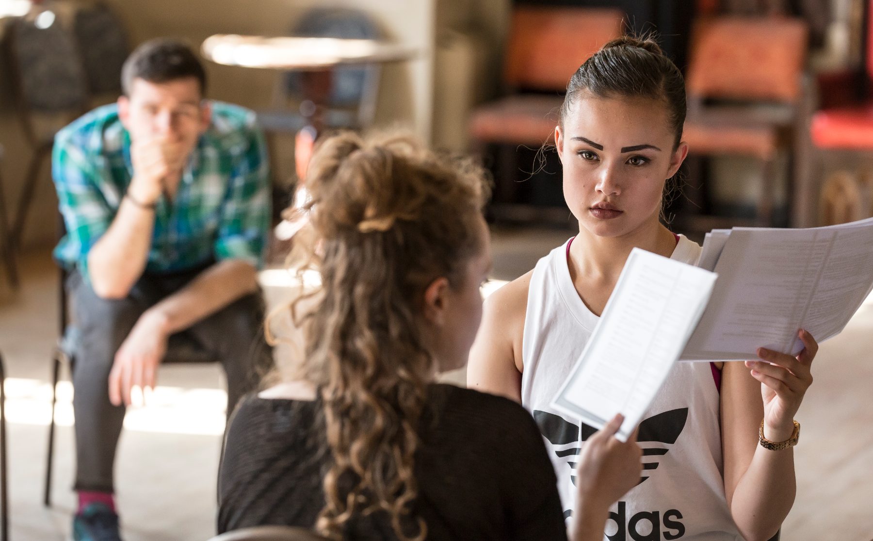 Two actors working with scripts while another watches