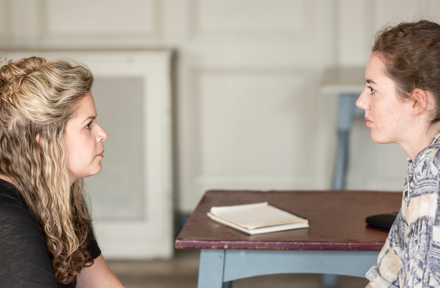 Two actors facing each other across a table, working in repetition